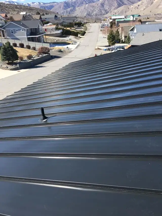 Close view of a dark standing-seam metal roof with a flashed vent pipe